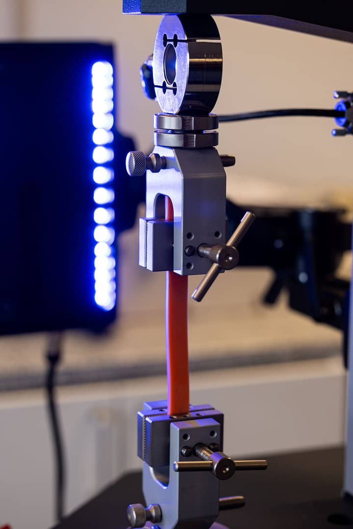 Vector Extensometer, Model U200 can be seen to be pulling an elastomer specimen being held between 2 universal testing machine grips.